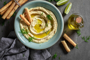 Traditional and yummy hummus with olives, grissini and herbs.