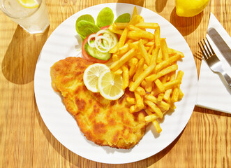 Wiener Schnitzel mit Pommes Frites im Biergarten im Sommer