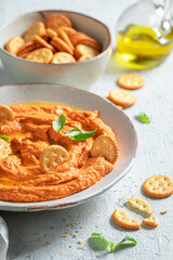 Fresh and spicy tomato hummus with crackers and herbs.