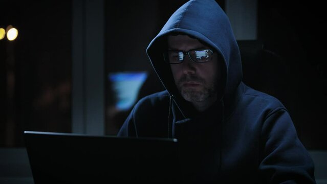 Hacker in a dark room, writes malicious code. An experienced programmer works alone.