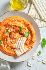 Tasty and homemade tomato hummus with breadsticks and herbs.