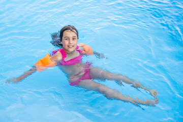 happy little girl having fun in the pool in swimming suit.