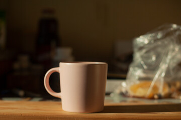 Cup on table. Kitchen details. Light on dishes. Morning drink.