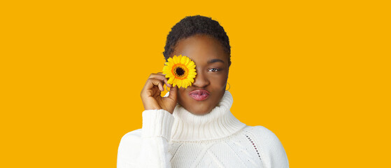  Portrait of a happy young woman holding yellow Gerbera daisy covering her eye with eyes closed
