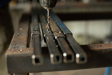 Drill drills steel. Drill makes hole in metal. Details of work in workshop.