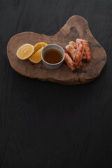 Crab served with sauce and sweet lemon on olive wood board