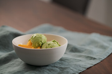 green matcha tea ice cream with fresh mango in white bowl
