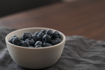 Fresh washed blueberries in white bowl on wood table