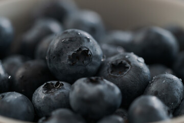 Closeup shot of washed blueberries in white bowl on wood table