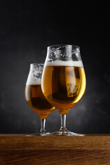 Two glasses of light beer on dark background. Selective focus