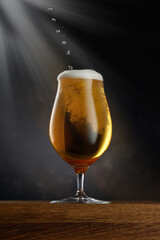 Glass of light beer on dark background. Selective focus