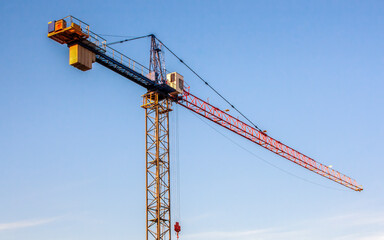 Construction crane. Diagonal view of the crane arm against the evening blue sky. Warm light