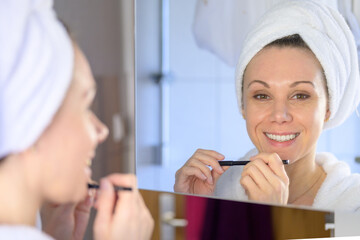 Happy woman with a vivacious smile applying her makeup