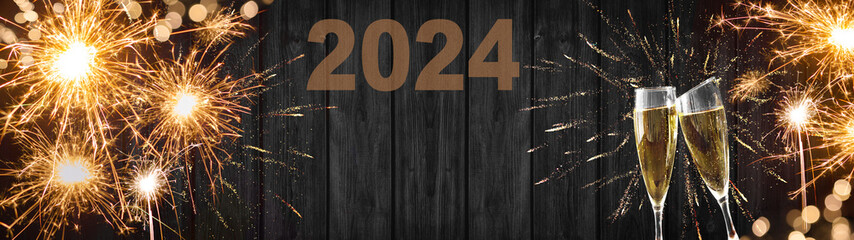 New Year, New Year's Eve 2024 Silvester background banner panorama long- Sparklers champagne glasses and bokeh lights on rustic wooden texture