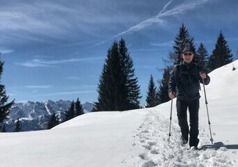 Bergwanderer (männlich) mit Wanderstöcken von vorne im Schnee