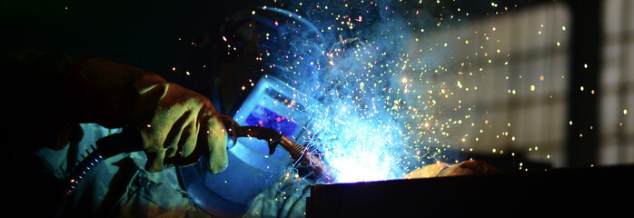 Workers wearing industrial uniforms and Welded Iron Mask at Steel welding plants, industrial safety first	
