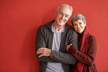Love is longevity. Shot of an affectionate senior couple standing in front of a red background.