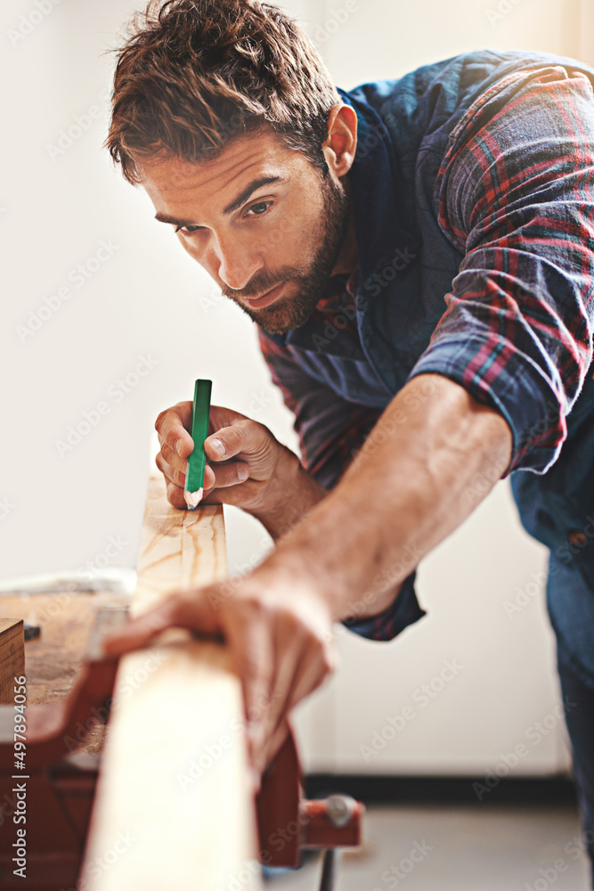 Poster measure twice, cut once. cropped shot of a carpenter making measurements on a plank of wood.