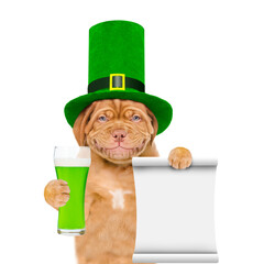 St Patrick's Day concept. Funny mastiff puppy wearing green cylinder  holds glass of beer and shows...