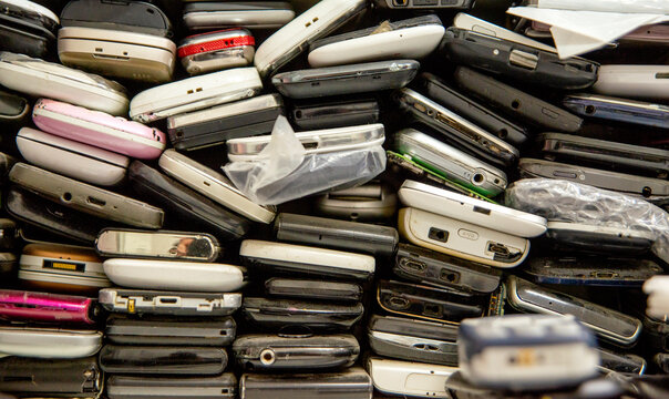 Used phones stacked on top of each other. Background of damaged mobile phones. A bunch of old smartphones. Equipment repair and maintenance services.
