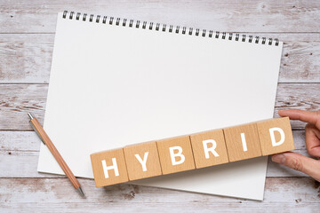 ハイブリッドのイメージ｜「HYBRID」と書かれた積み木、ノート、ペン、手