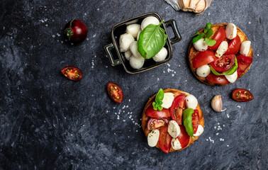 Open sandwiches with cherry tomatoes, mini mozzarella, fresh basil leaves, caprese on bread, Traditional italian appetizer or snack, antipasto. banner, menu, recipe place for text, top view