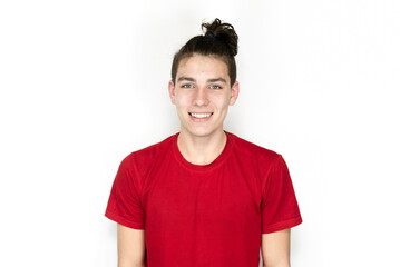 Obraz premium Handsome teenager boy 16-18 years old in red t-shirt with modern hairstyle smiling on light background. The concept of joy and happiness in a teenage boy