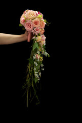 Unique cascading wedding bouquet in a womans hand on a black background © ovbelov1972