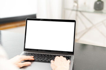 Cropped view of the young woman using laptop for work indoors. Blank white laptop screen for inserting text. Technologies concept