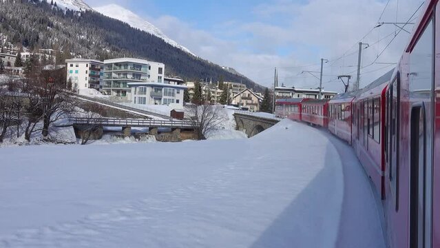 Arrival of the train at Davos Platz station. The red train travels along the snow-covered valleys of the Swiss Alps.