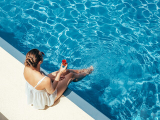 Fashionable woman sitting by the pool on the empty deck of a cruise liner. Closeup, outdoor, view...