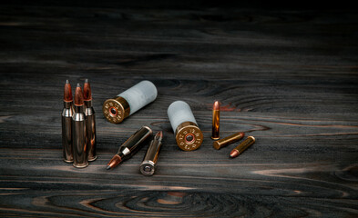 Various types of ammunition on a wooden surface. Cartridges for weapons. Dark back. - obrazy, fototapety, plakaty