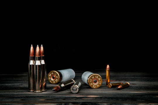 Various types of ammunition on a wooden surface. Cartridges for weapons. Dark back.