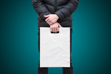 A man holds a mockup white plastic bag. A man with a package on isolated background