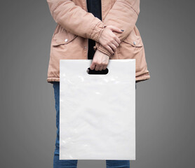 The girl is holding a mockup white plastic bag. A girl with a package on isolated background