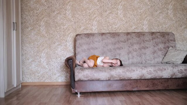 Funny children siblings jump and play together. Toddler and baby in a reusable diaper at home in a real interior. Sibling relationships