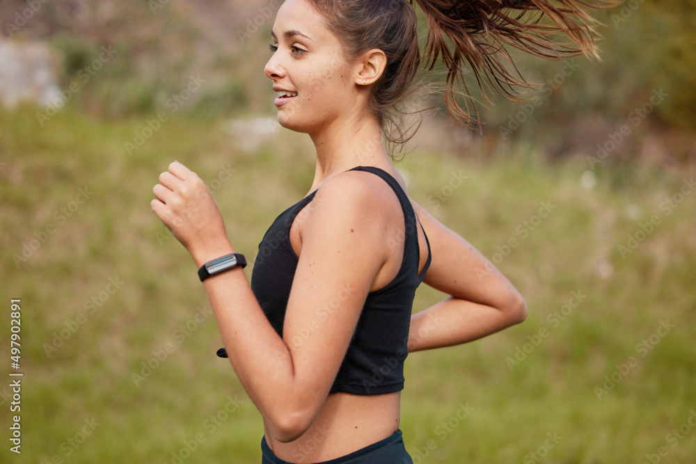 Wall mural Sprinting straight towards a healthier lifestyle. Shot of a sporty young woman running outdoors.