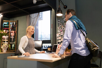 a flower shop worker greets a customer who has come to buy a bouquet of fresh cut flowers