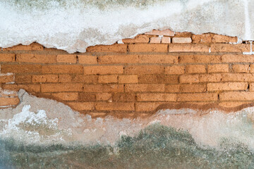 Old red brick wall with peeling plaster