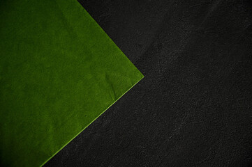A beautiful green napkin lies on a black texture table with a corner to the side. Space for labels.