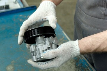 Spare parts. An auto mechanic inspects a new power steering pump. Repair and maintenance of the car...