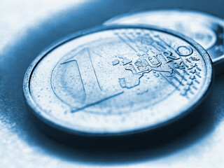 Euro coins. The focus is on the inscription with the name of the Euro Zone currency on the 1 euro coin. Closeup. Blue tinted illustration about the economy and money of the European Union. Macro