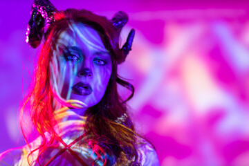 Beautiful young woman with makeup zodiac signs of Capricorn or Aries or Taurus. Girl with horns on head neon light