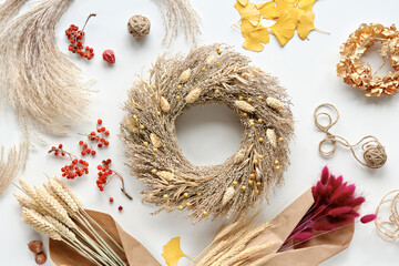 Autumntime natural decor. Dry grass wreath. Of white flat lay with ginkgo leaves. Fall background...