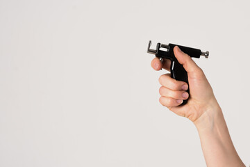 A woman beautician holds a gun for ear piercing in her hand, ear piercing with a gun