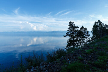 Lake Baikal. Trees on the lake, water surface and blue sky. Evening landscape. Russia