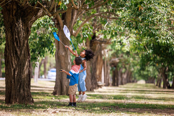 Little boy and girl with butterfly net catching butterflies in the park