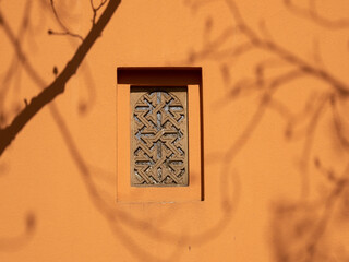 Patterned window on a brown wall.