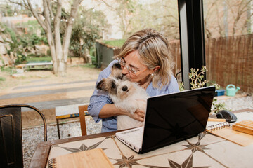 Adult  woman working at home office remotely sitting with best friend dog puppy at garden backyards