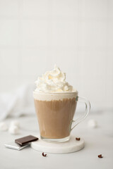 hot coffee with milk and whipped cream in a glass cup